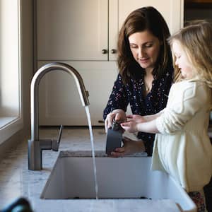 Mom and daughter wash hands at kitchen sink