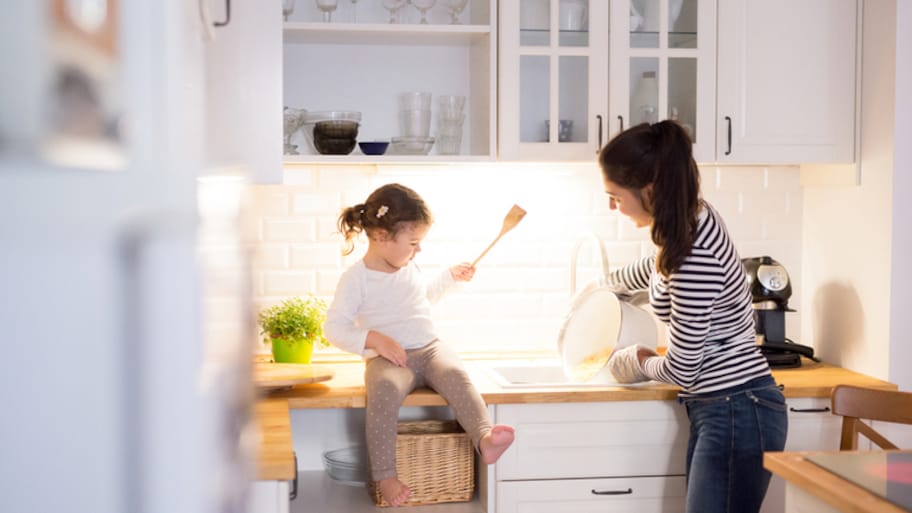 Mother and daughter laughing at kitchen sink