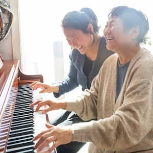 A mother and her daughter playing the piano