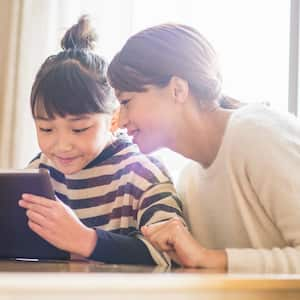 A mother and her daughter playing with an electronic device 