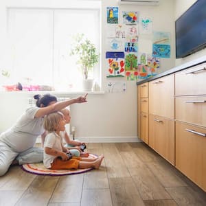 A mother with her kids sitting on the floor watching TV