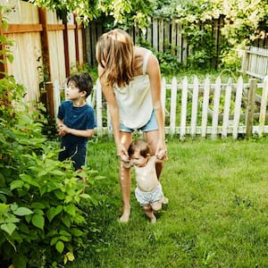 A mother with her sons picking raspberries in their garden