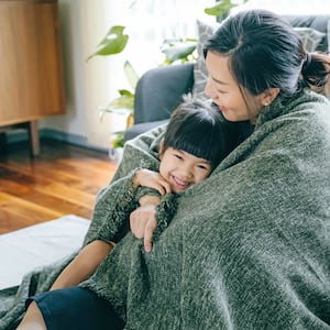 Young mother and daughter wrapped in blanket