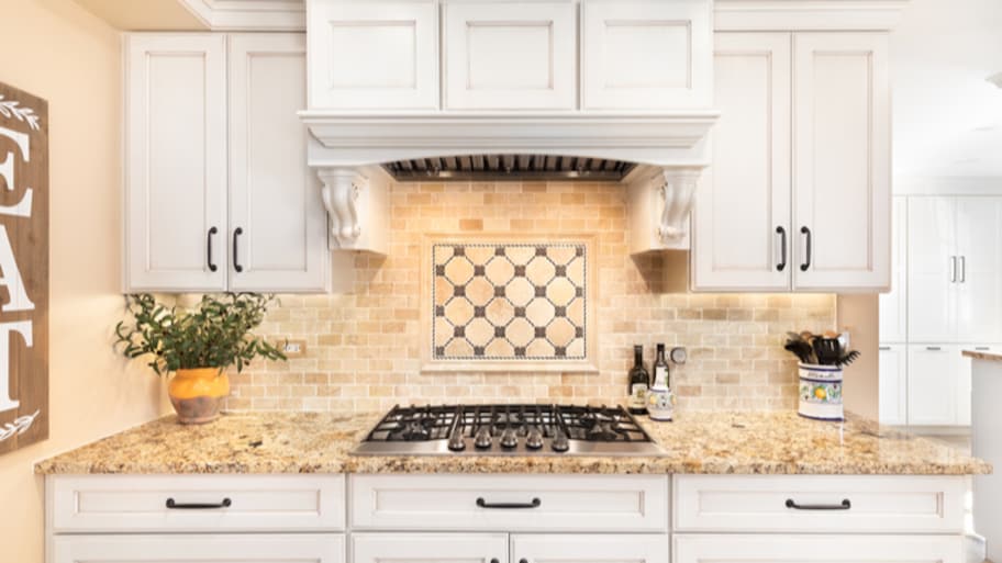 Tan natural stone backsplash and kitchen stove