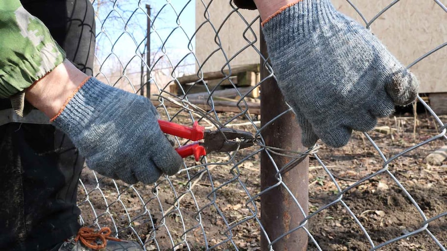 A person attaching an extension to a chain link fence