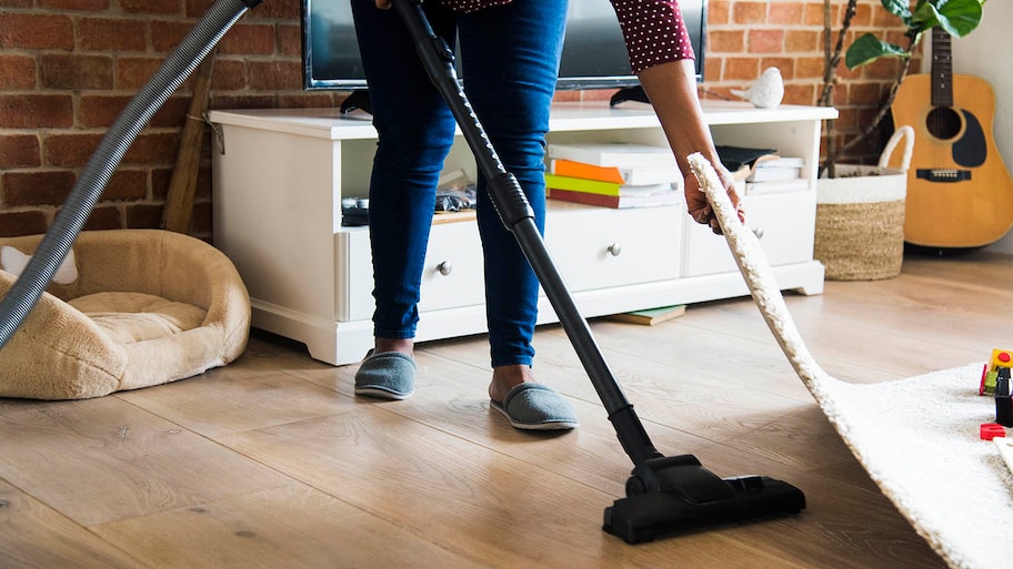 woman vacuuming under rug