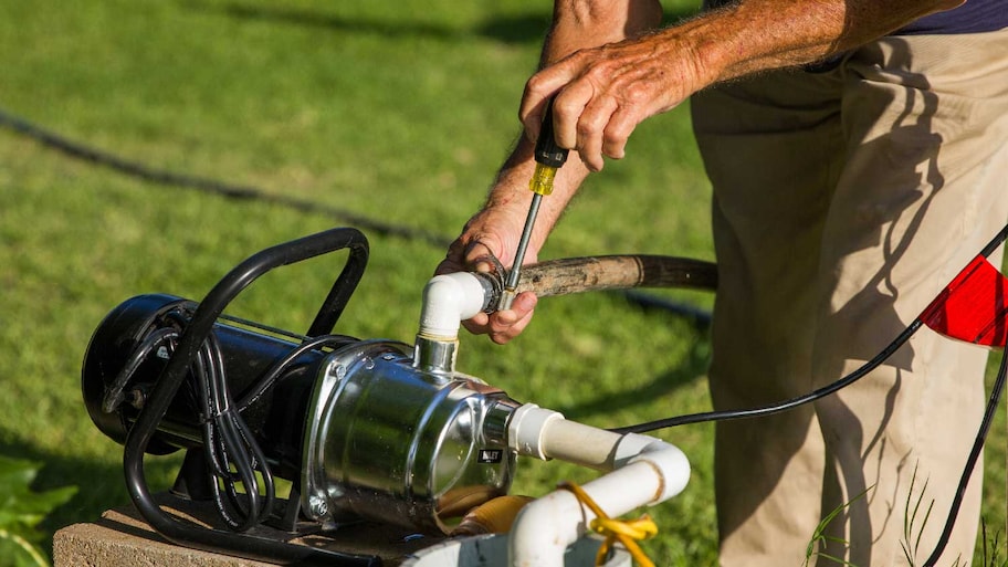 A person repairing a sprinkler pump