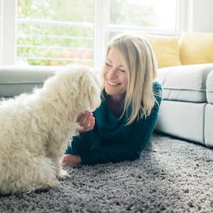 woman sitting on the carpet playing with her dog