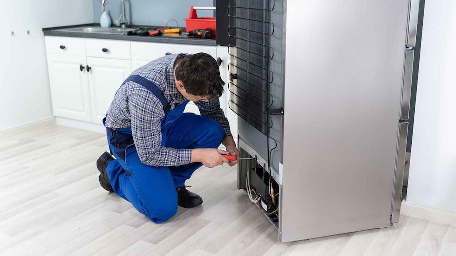 Technician in the kitchen repairing home refrigerator