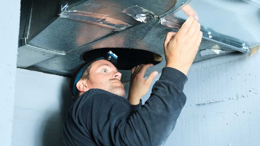 A professional inspecting an air duct