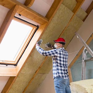 A professional installing rock wool insulation in the attic