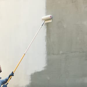 A professional painting a house wall with a roller