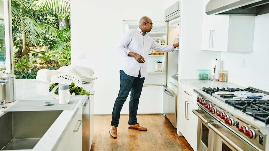 Man in the kitchen putting groceries in the refrigerator