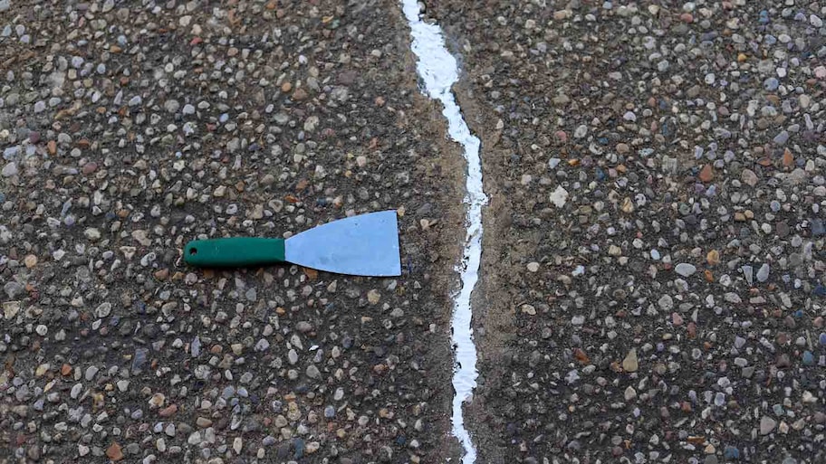 putty knife on cracked driveway