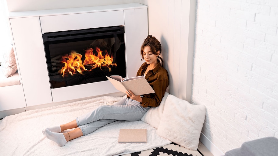 Woman reads a book by a roaring fire