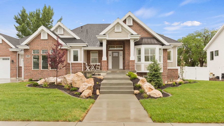 A red brick house with intricate details and stairs leading to the front porch