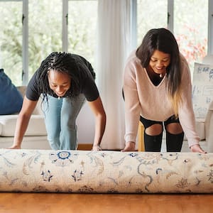 Girlsr olling up rug on wood floor