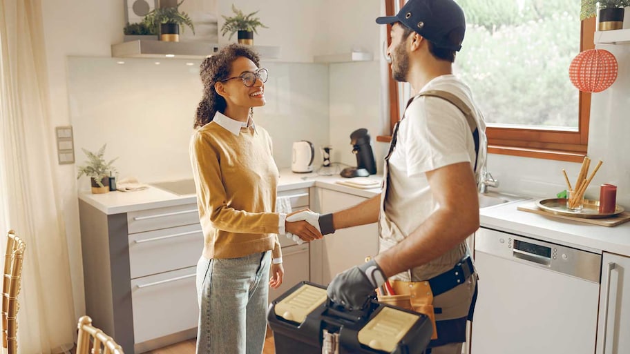 Professional plumber is shaking hands with happy client