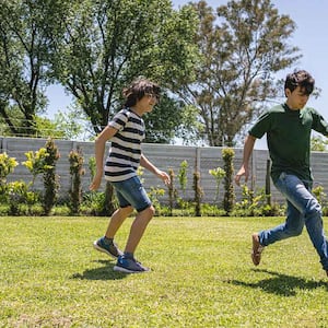 Siblings playing soccer in the yard