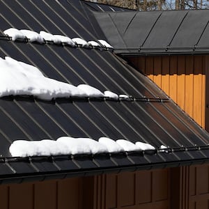 Closeup of black metal roof of house with snow