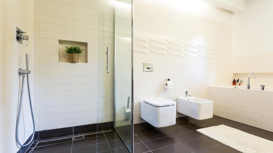 A spacious bathroom with a shower and black tiles on the floor