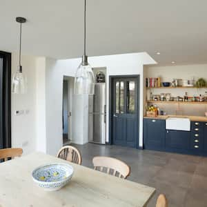 A spacious transitional kitchen with blue cabinets and wooden countertops