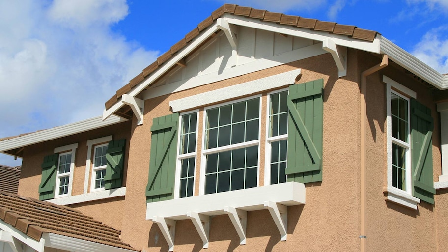 Upclose shot of stucco house with green shutters