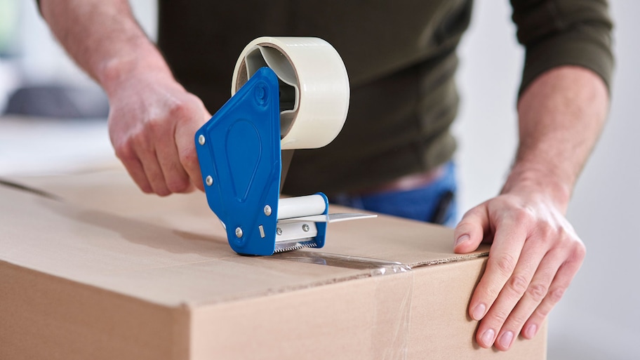 Applying packing tape on cardboard box