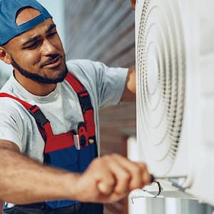 Technician repairs external ac unit