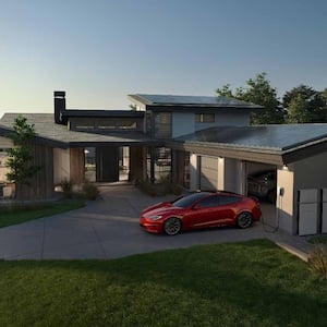 A Tesla Powerwall+ next to a residential garage