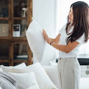 Woman in the living room tidying up sofa cushions