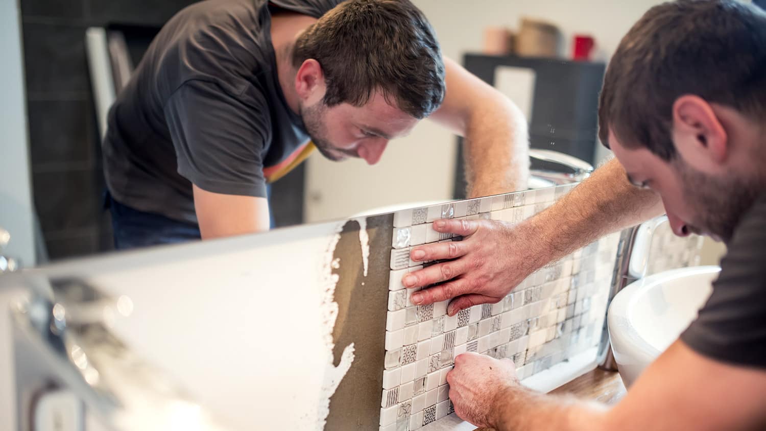 Tile contractor installs square tiles under bathroom mirror