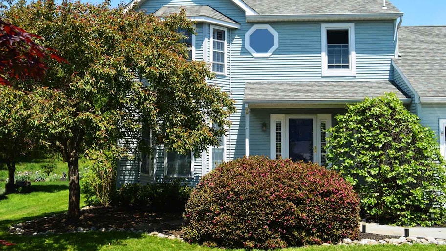 A two-story house with trees in its yard