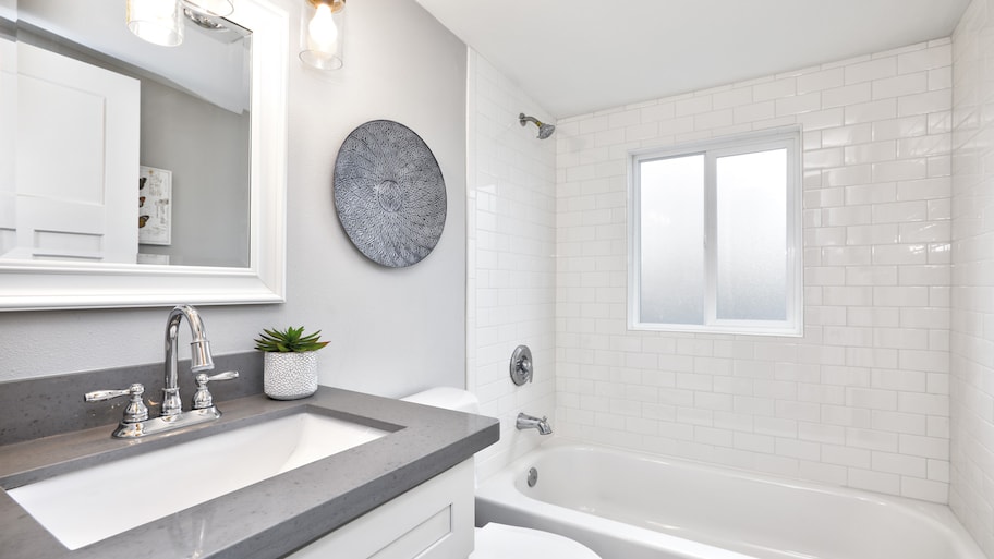 Updated bathroom with grey countertop and white tile surround