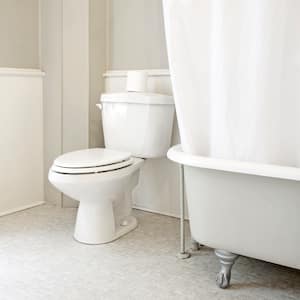 shot in white bathroom of white toilet and partial view of bathtub with white accents