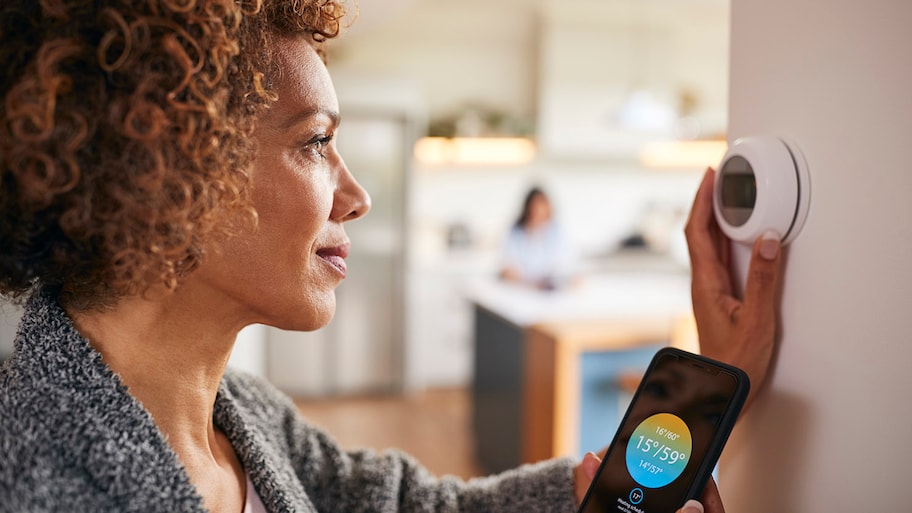 woman adjusting a smart thermostat