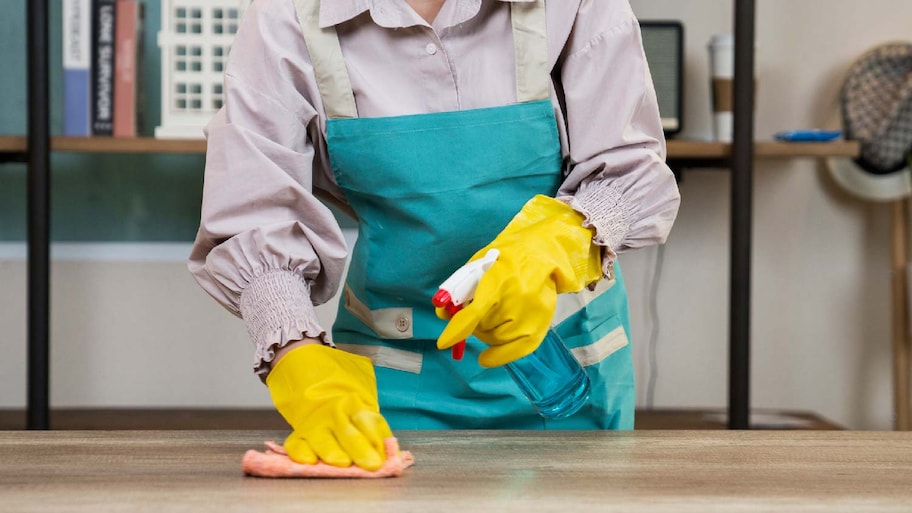 A woman applying a cleaning solution on a wooden surface