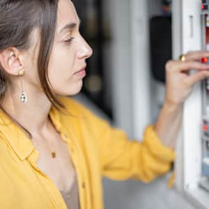 Woman checking breakers in a circuit breaker box