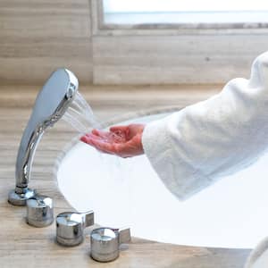 Woman checking temperature touching running water