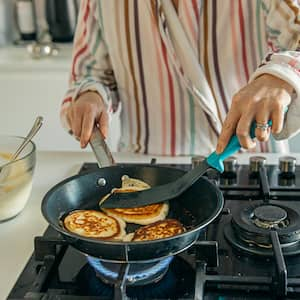 A woman cooking pancakes on a gas stove