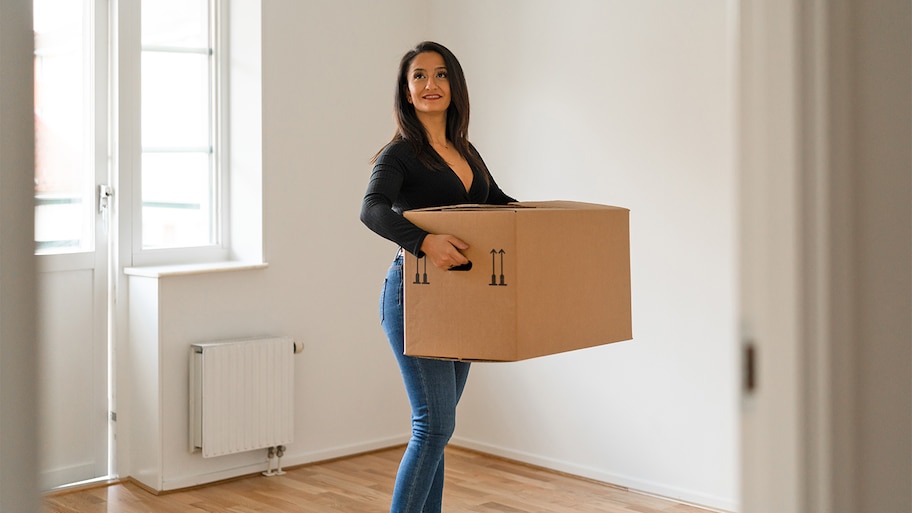 woman carrying last box from empty apartment