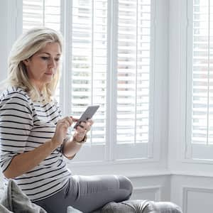 woman using smartphone in front of living room window