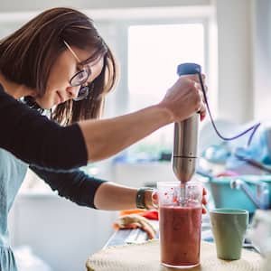 woman making a smoothie with an electric blende