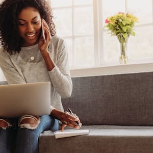 A woman talking on the phone while looking at her laptop