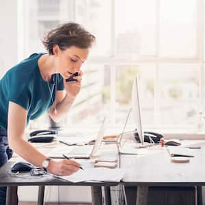 A woman taking notes while talking on the phone