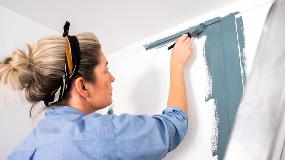 woman painting wood paneling trim