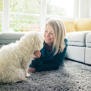 Smiling woman petting her dog in living room