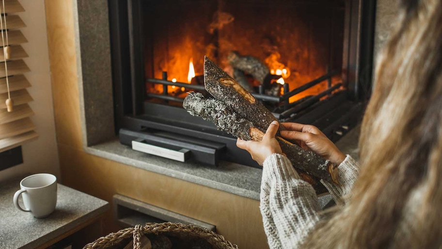 A woman putting wood logs in the fireplace