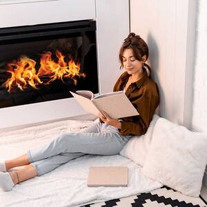 Woman reading a book and relaxing near a gas fireplace 