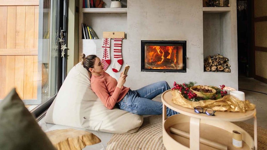 Woman sitting by the fireplace reading a book